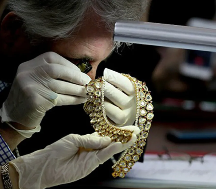 Joyer revisando collar de oro con lupa. Sobre Nosotros.