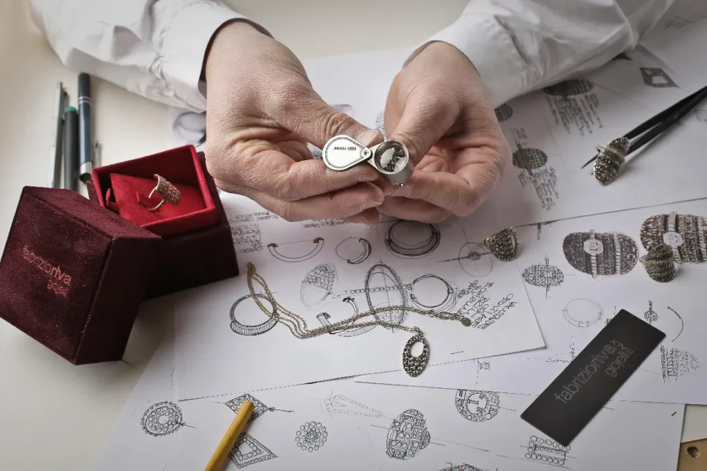 Diseño de joyas y bocetos para compraventa de oro. Joyero examinando un anillo con lupa.